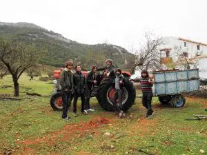 La banda lojeña posa delante del tractor del hotel rural Huerta Nazarí. En el centro, conduciendo la máquina, está sentado el productor musical Ricky Faulkner. Al fondo puede verse la sierra de Parapanda con sus pinares, y a la derecha, la fachada blanca del hotel. Es un día de noviembre en el que ha llovido y la tierra está mojada.